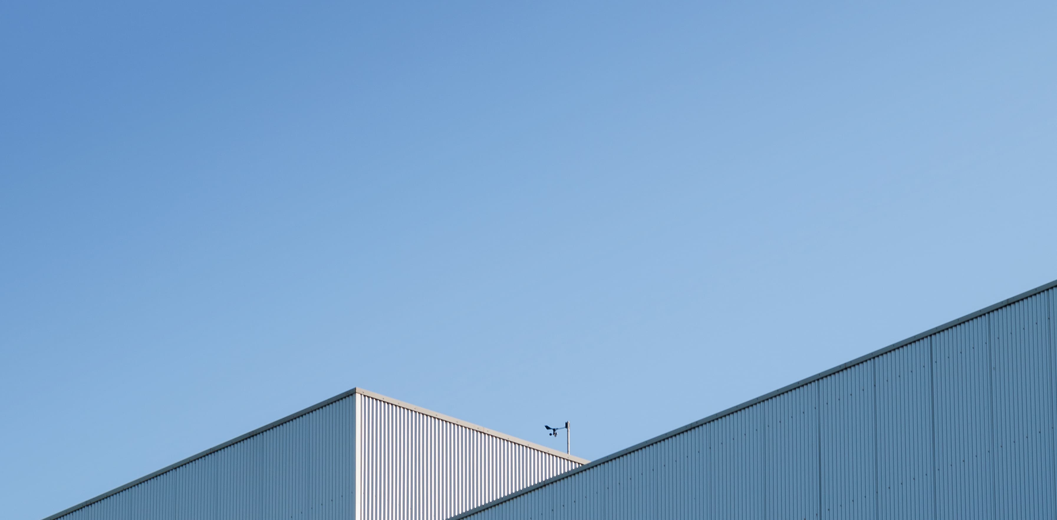 Angular metal building tops against a clear blue sky, with a small weather vane visible on one of the roofs.