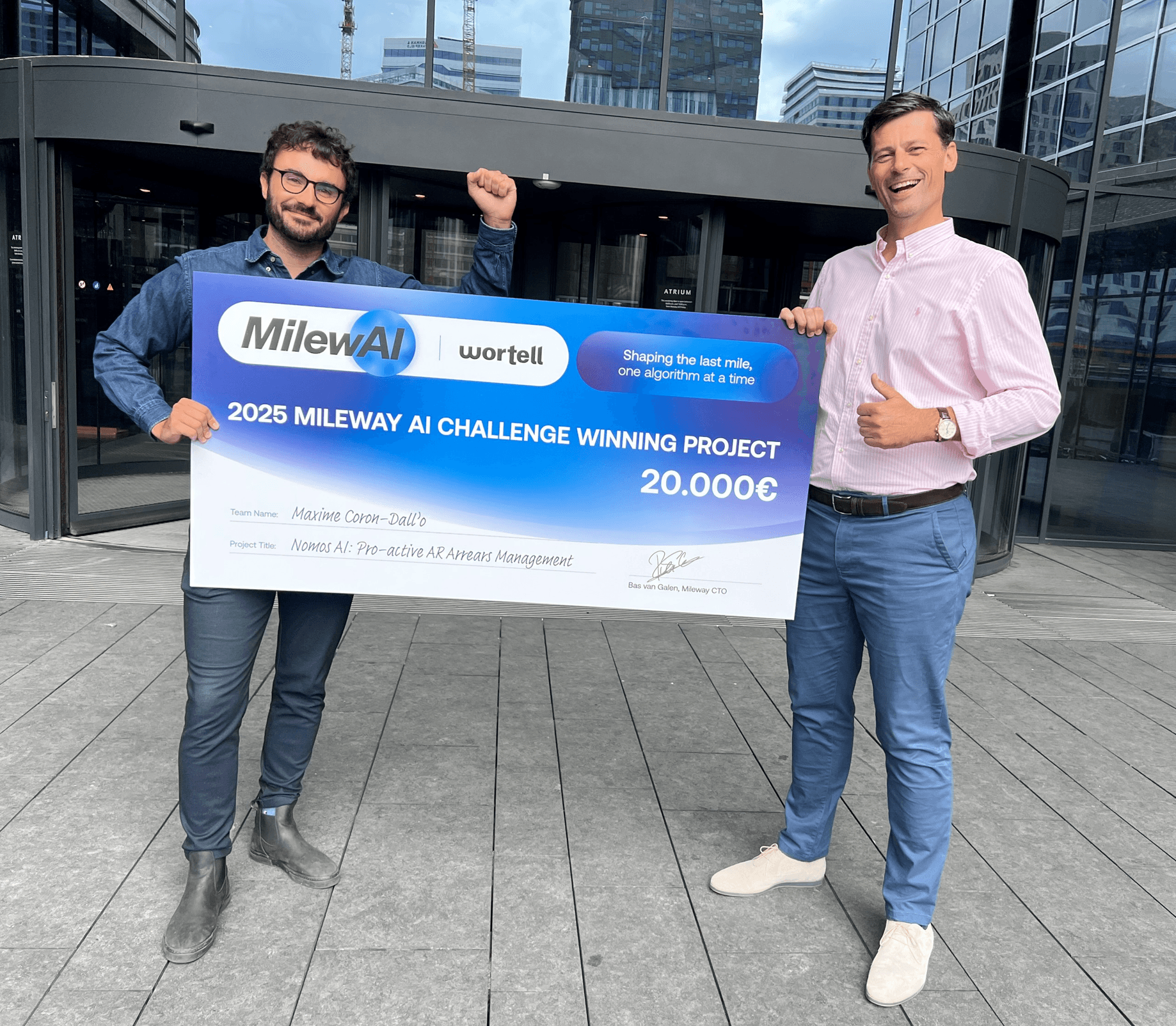 Två män står utanför och håller en stor check på 20.000 euro, som tilldelats det vinnande projektet 2025 Mileway AI Challenge.